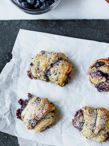overhead image of blueberry crescent rolls on piece of parchment paper